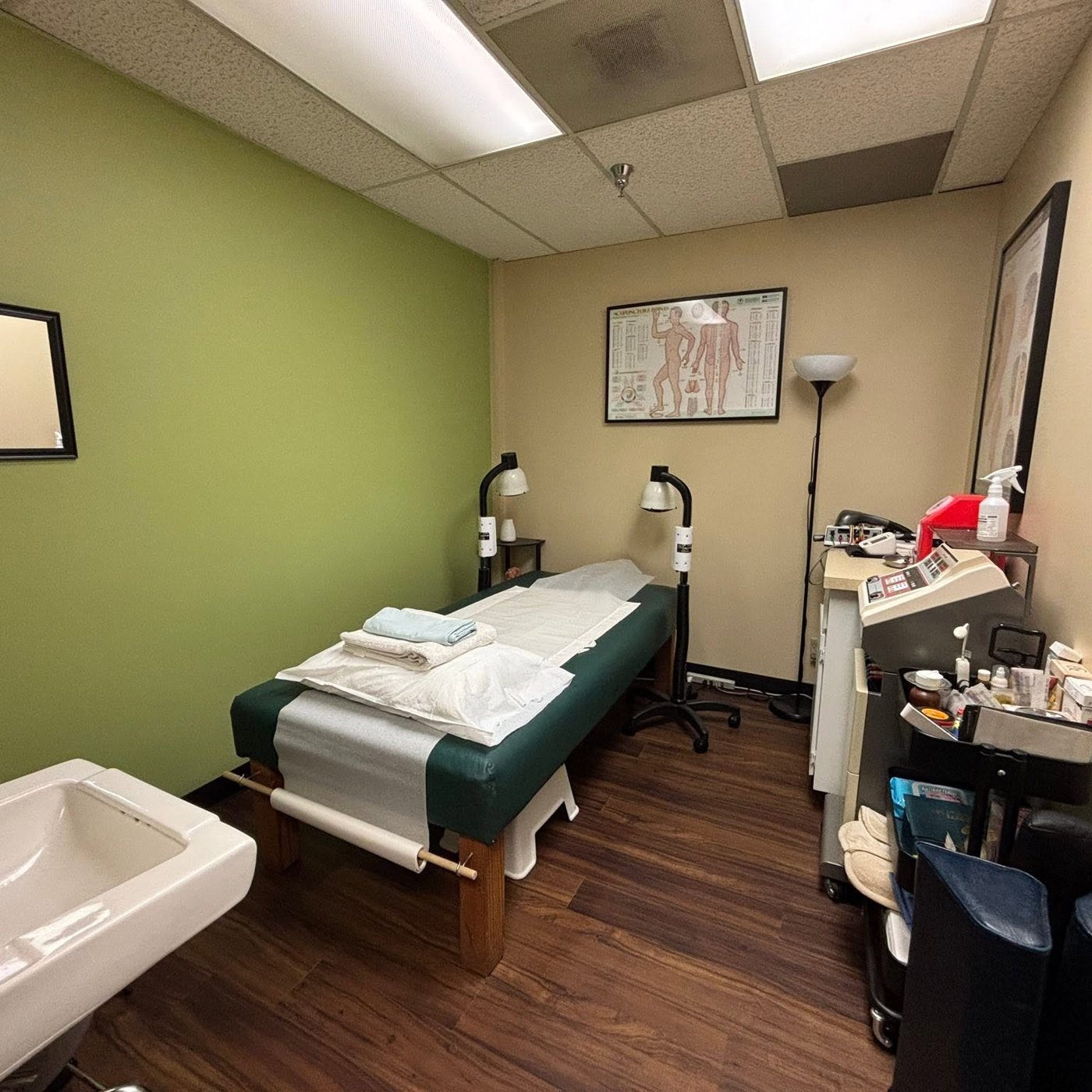A private treatment room at JP Acupuncture with a treatment table, fresh linens, and warming heat lamps